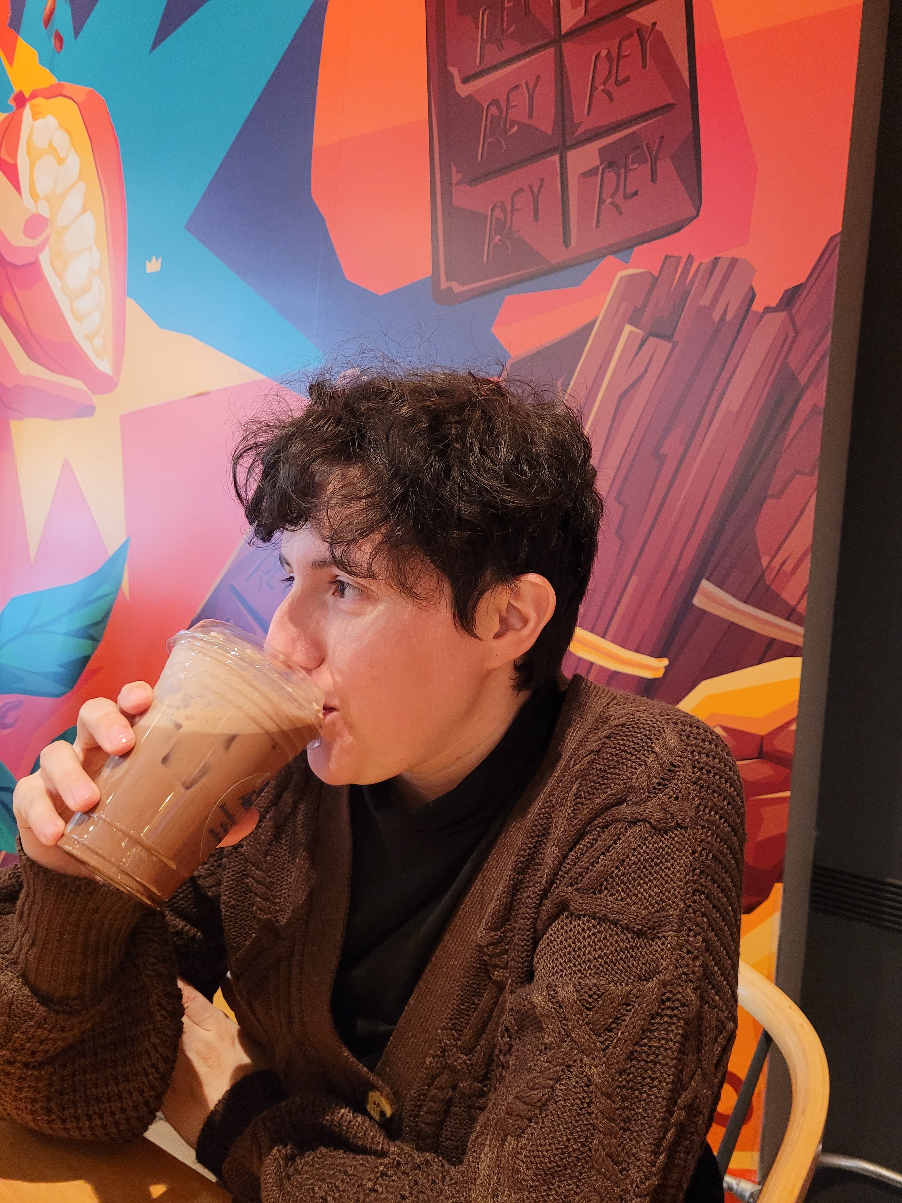 A portrait-style headshot of Papel Arcano owner Jack Saucedo, drinking coffee.