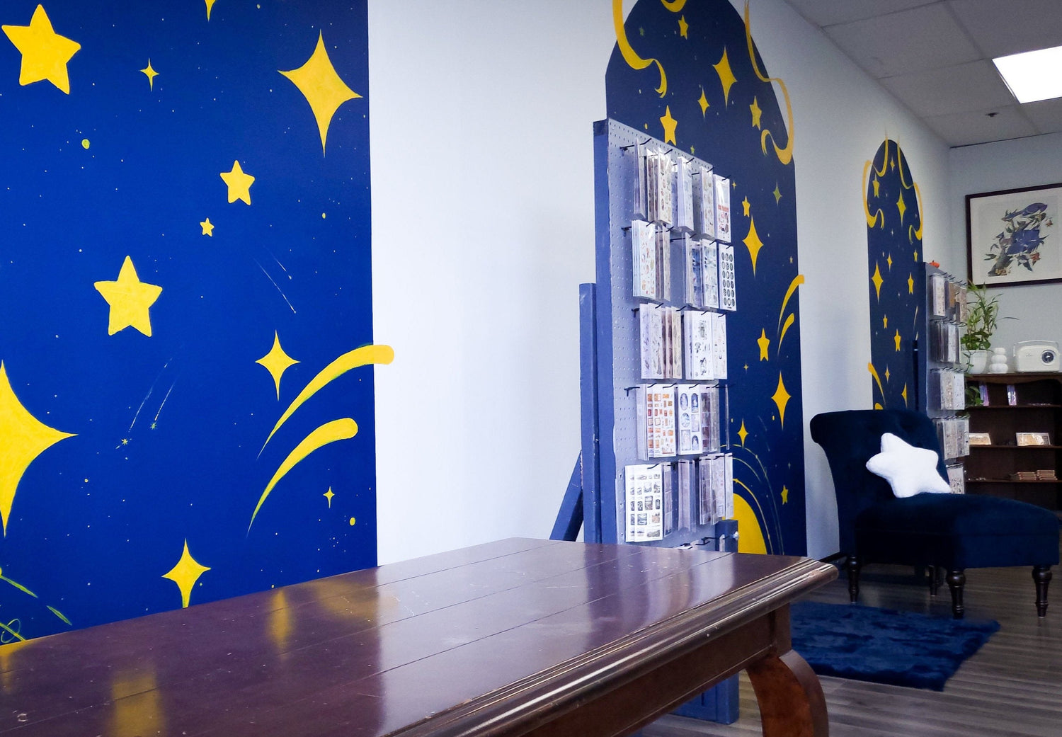 Papel Arcano interior showing starry-themed murals and a display case of sticker sheets.