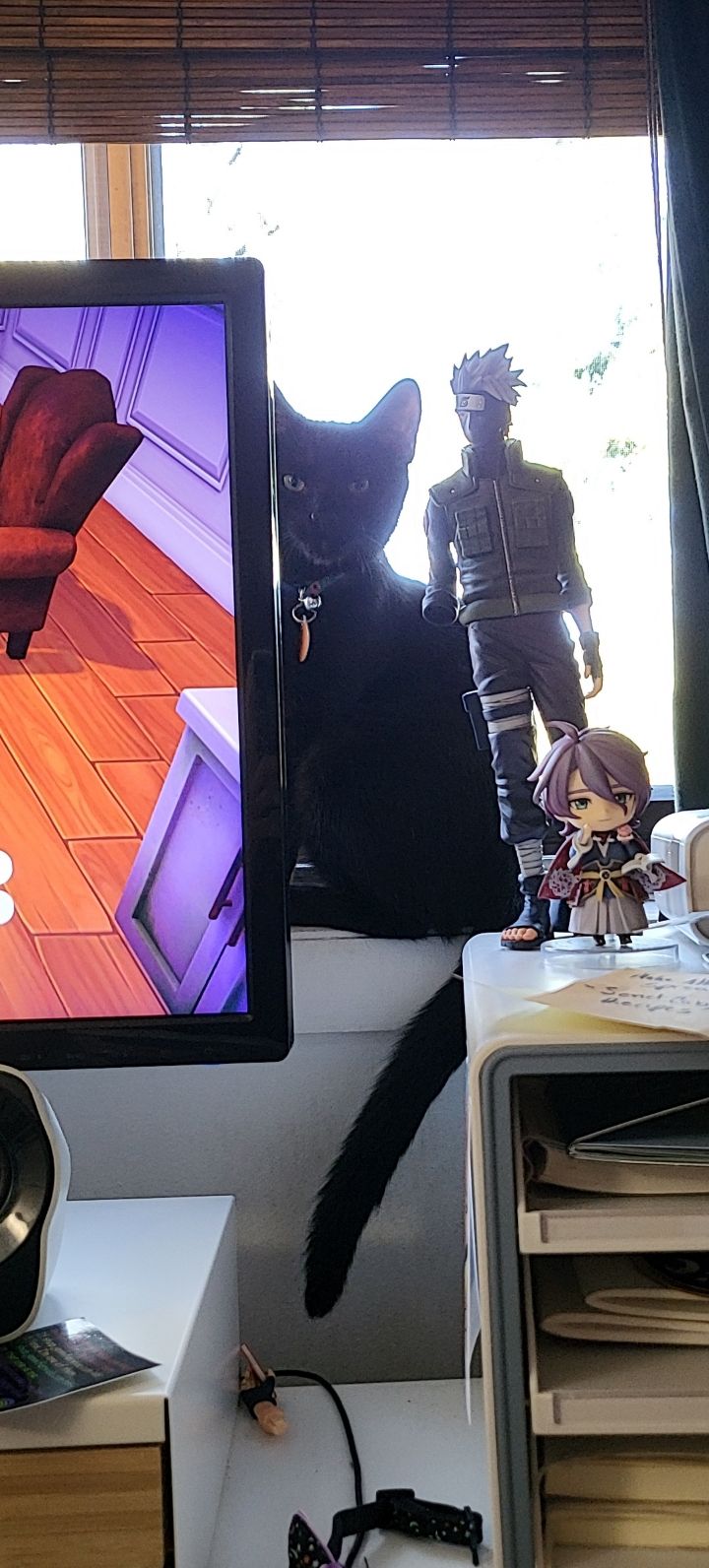 The Papel Arcano official mascot, Pepita, a black cat sitting in front of a window peeking out from behind a computer monitor.